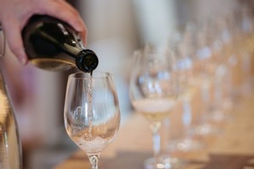 Mari server pouring wine into a row of glasses